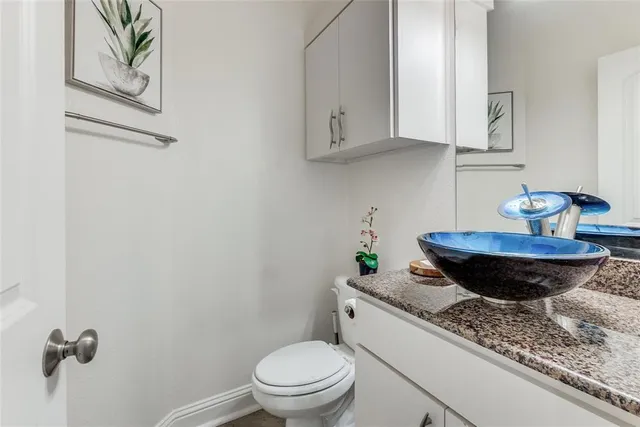 a bathroom with a granite countertop sink and a toilet