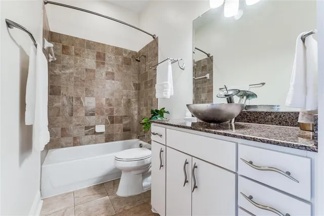 a bathroom with a granite countertop sink a toilet a mirror a bathtub and shower