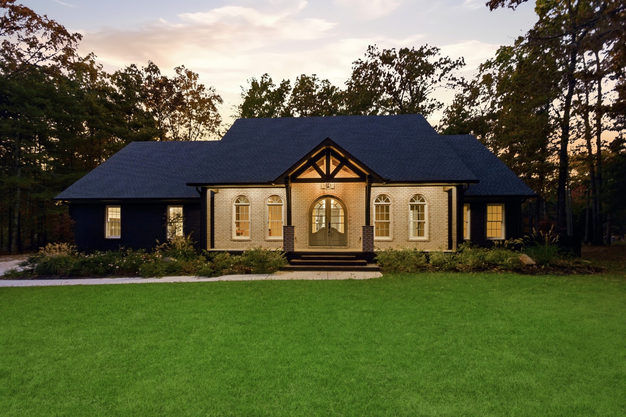 a front view of a house with a garden and trees