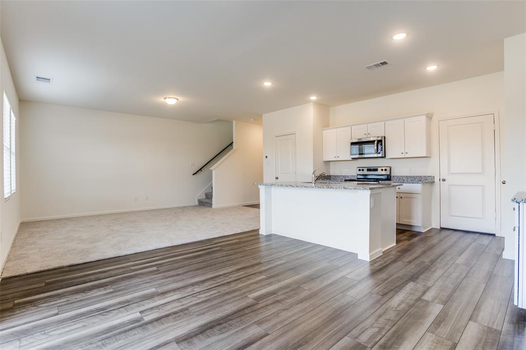 622 Colgate Circle Princeton, TX 75407 - Photo 11 of 12 Kitchen with open floor plan, an island with sink, white cabinetry, light wood-style floors, and appliances with stainless steel finishes