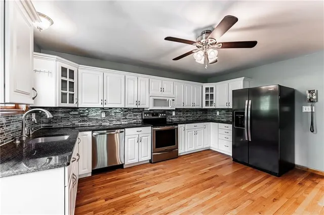 a kitchen with stainless steel appliances granite countertop a sink dishwasher a refrigerator and a stove