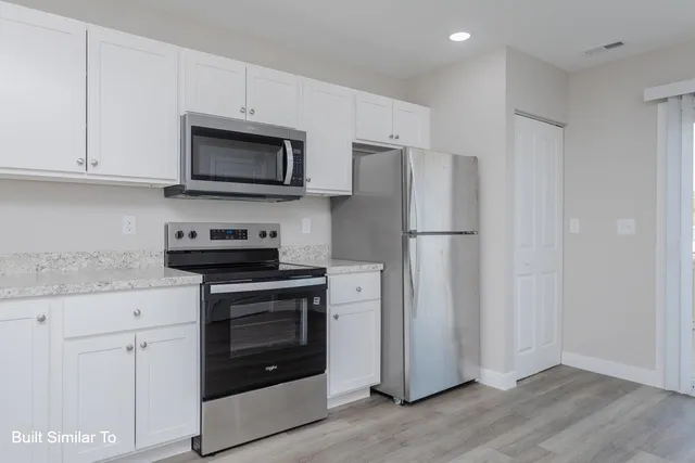 a kitchen with stainless steel appliances granite countertop a refrigerator stove and white cabinets