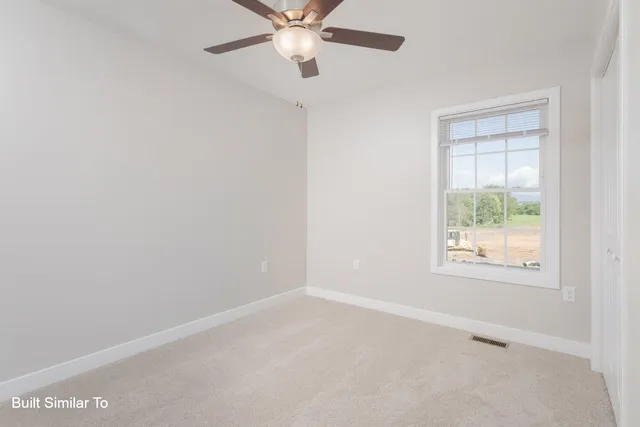 an empty room with a window and a ceiling fan