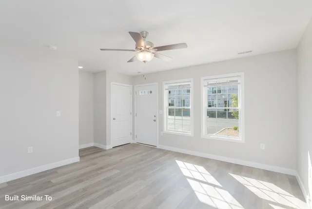 a view of an empty room with a window and wooden floor
