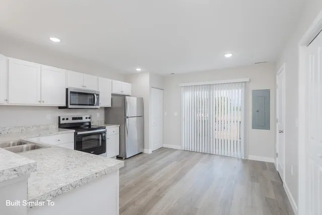 a kitchen with stainless steel appliances granite countertop a refrigerator oven a sink with granite countertops and wooden floor