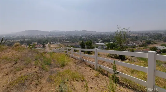 a view of a dry yard with trees in the background