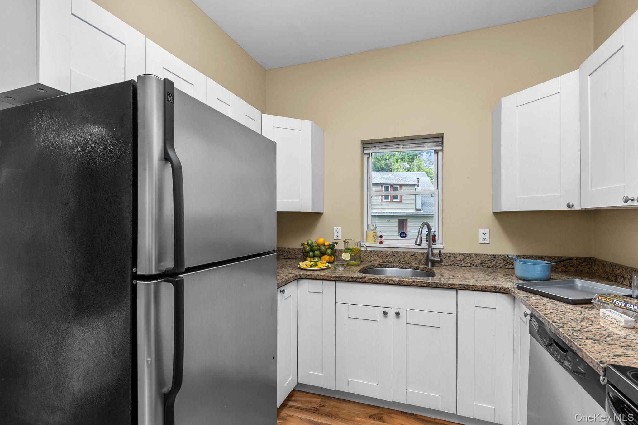 10 Batavia Road Patterson, NY 12563 - Photo 15 of 42 Kitchen featuring white soft-close cabinetry, granite-finish countertops, stainless steel sink with a gooseneck faucet, and wood-finish flooring.