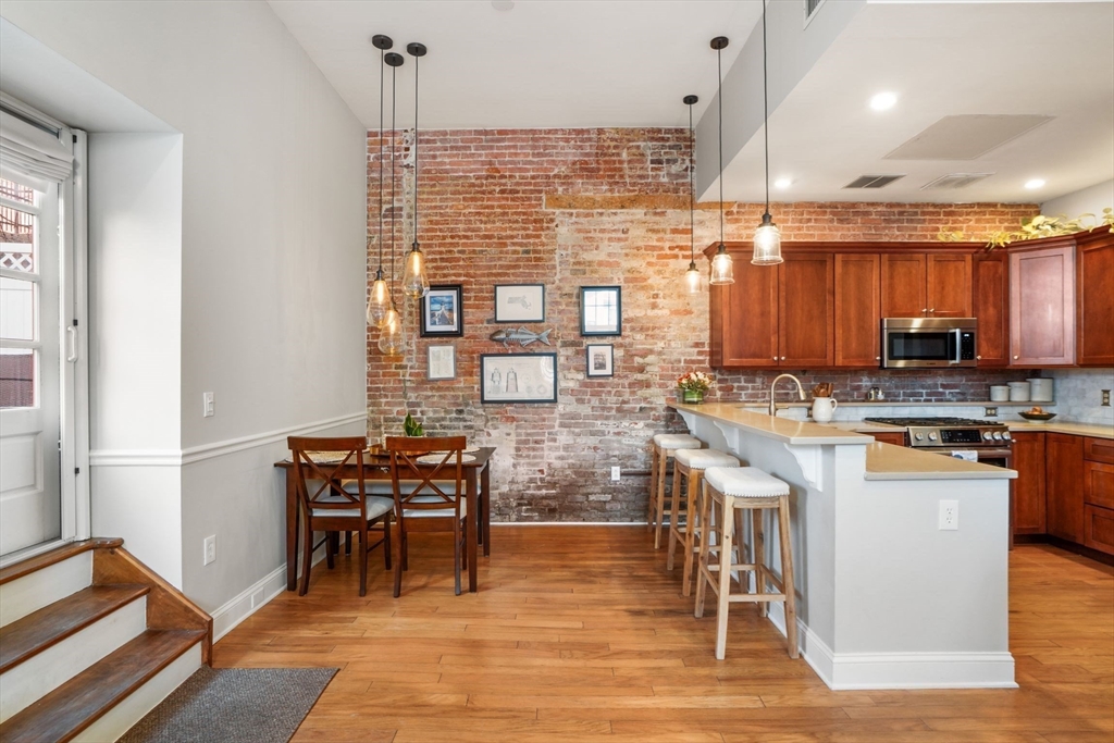 68 Baldwin Street, Unit 1 Boston, MA 02129 - Photo 5 of 19 a kitchen with stainless steel appliances kitchen island granite countertop a table chairs sink and cabinets