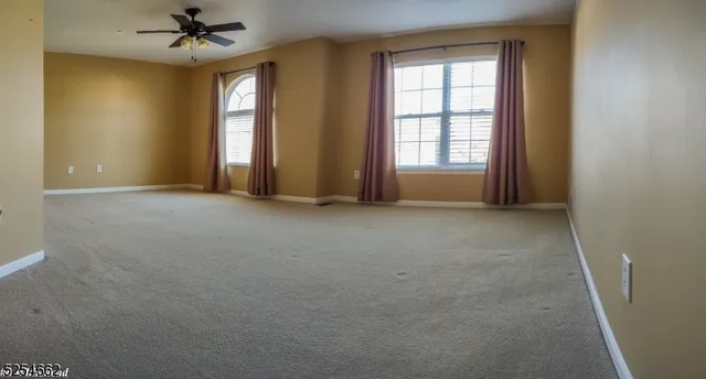 an empty room with windows and fan