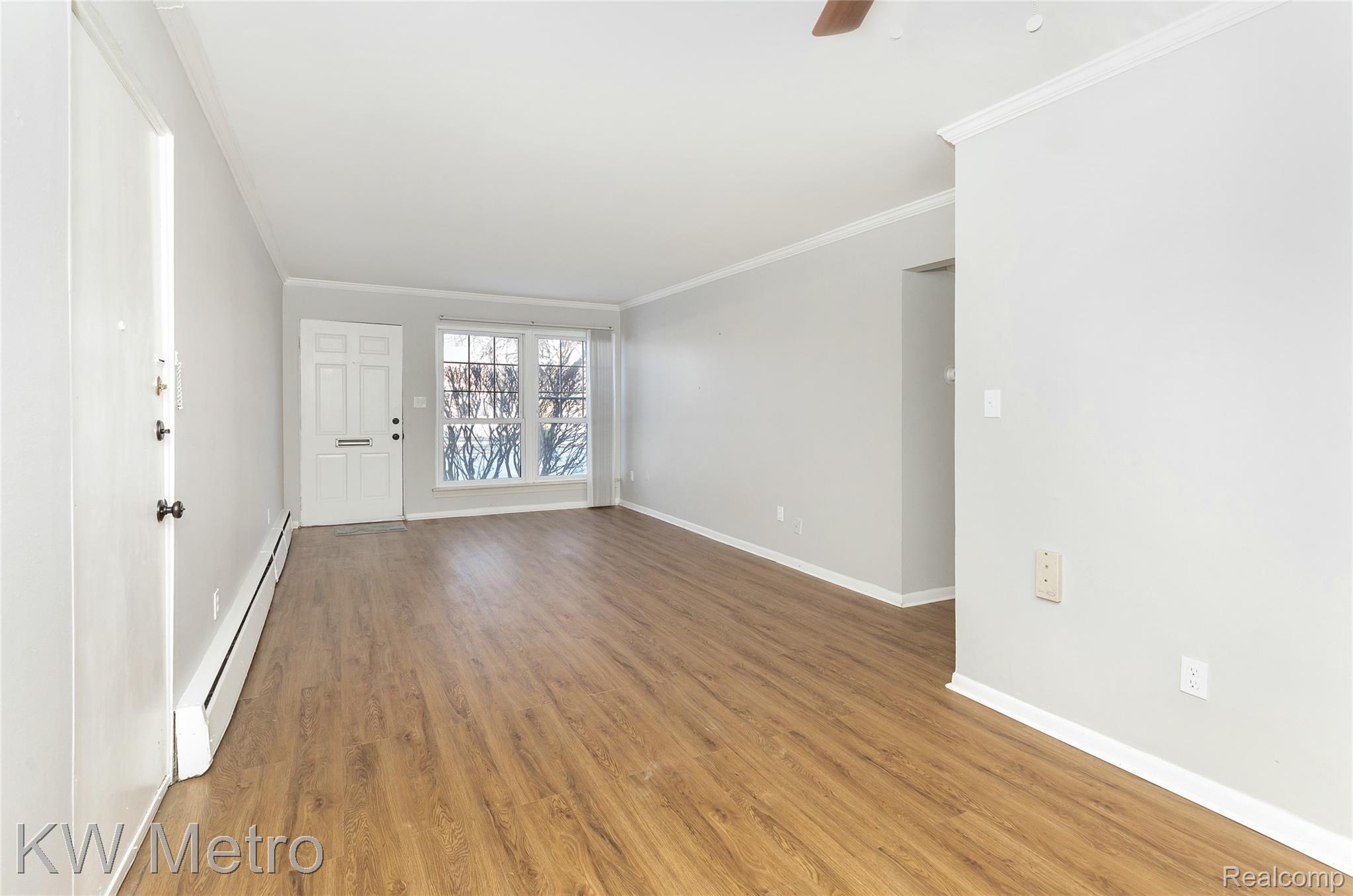 2817 West 13 Mile Road Royal Oak, MI 48073 - Photo 3 of 21 Unfurnished room featuring a baseboard heating unit, crown molding, light wood-type flooring, and a ceiling fan