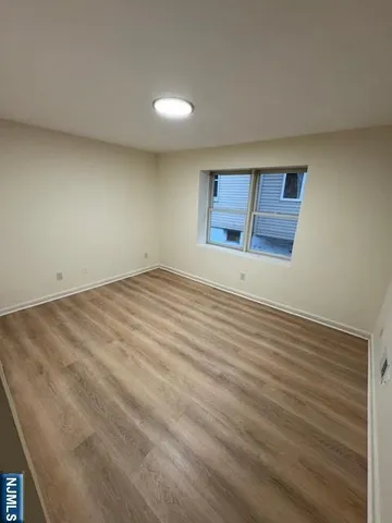 a view of an empty room with wooden floor and windows