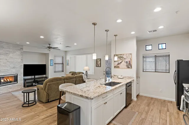 a kitchen with stainless steel appliances kitchen island granite countertop a refrigerator oven a sink dishwasher and wooden cabinets with wooden floor