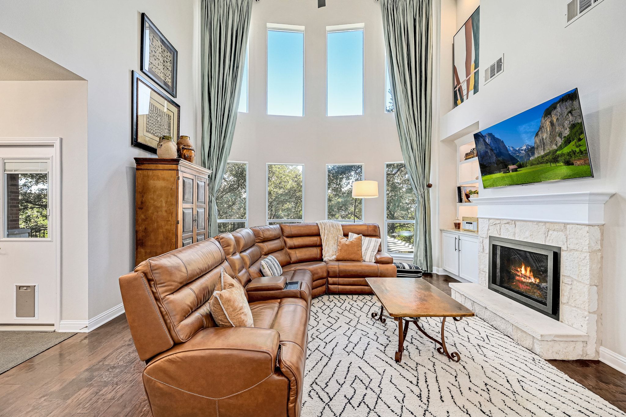 7112 Via Correto Drive Austin, TX 78749 - Photo 3 of 29 Living area featuring a fireplace, dark wood flooring, a high ceiling, and healthy amount of natural light with a view into the greenbelt