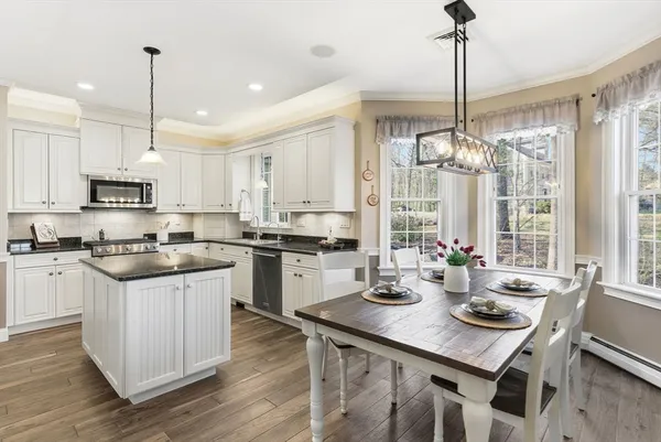 a kitchen with a stove a sink dishwasher a kitchen island with chairs and cabinets