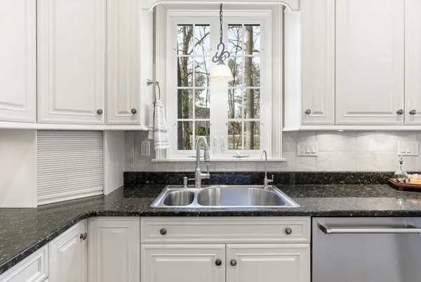 a kitchen with granite countertop white cabinets and a sink