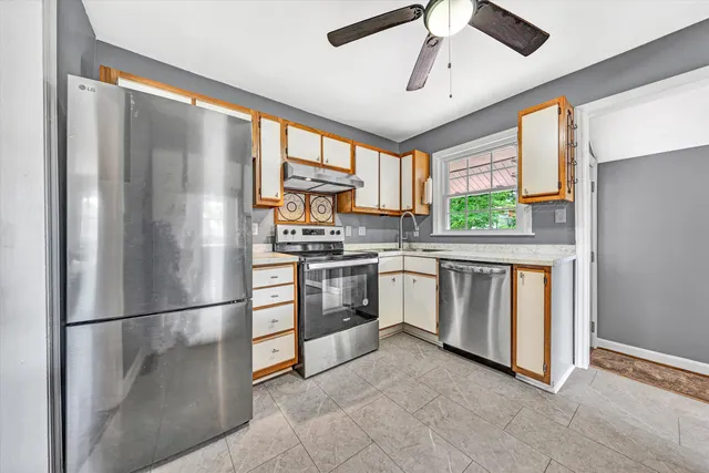 a kitchen with white cabinets and window
