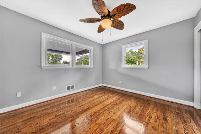 a view of an empty room with a window and wooden floor