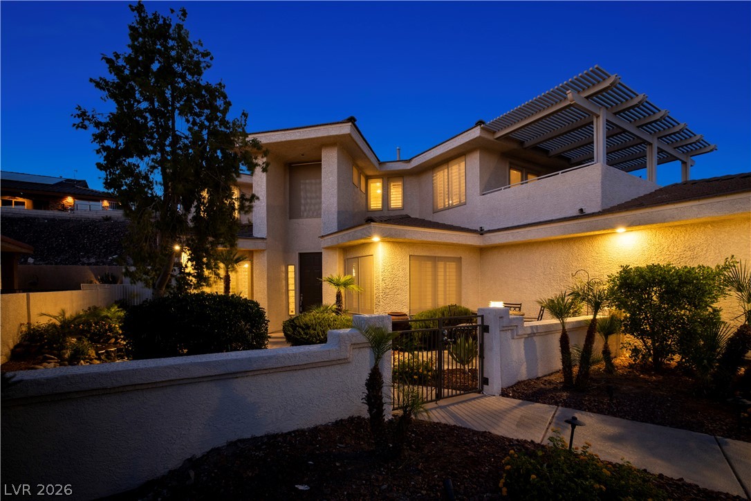 1135 Calico Ridge Drive Henderson, NV 89011 - Photo 76 of 86 Illuminated at dusk, a multi-level residence with private gate entry and pergola-covered balcony awaits.
