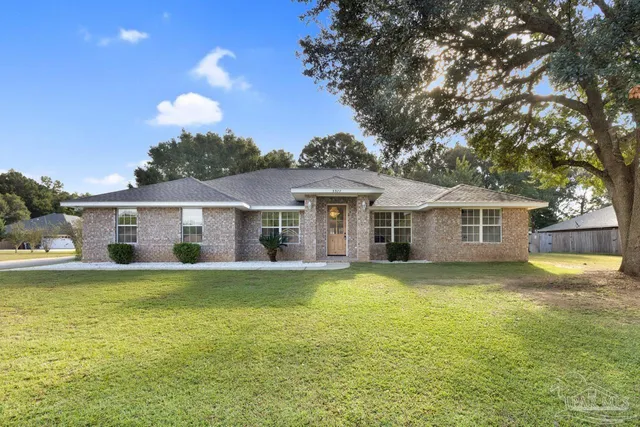 a front view of a house with a garden and trees