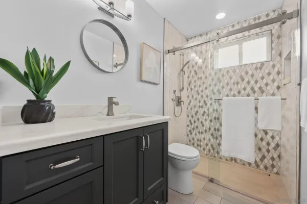 a bathroom with a granite countertop sink a toilet and shower