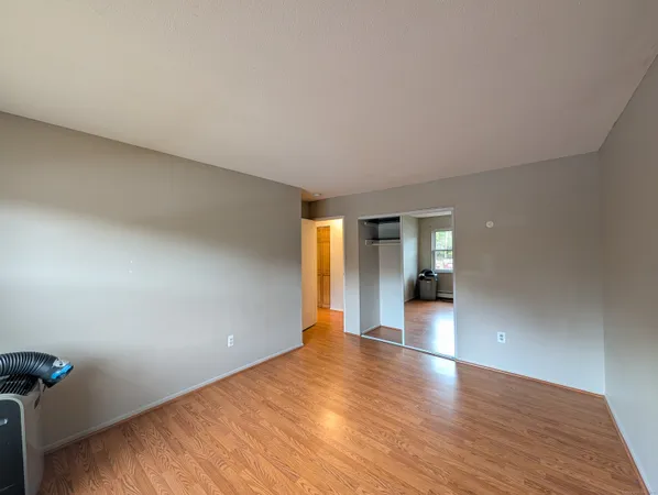 a view of an empty room with window and wooden floor