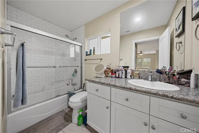 a bathroom with a granite countertop sink toilet mirror and shower