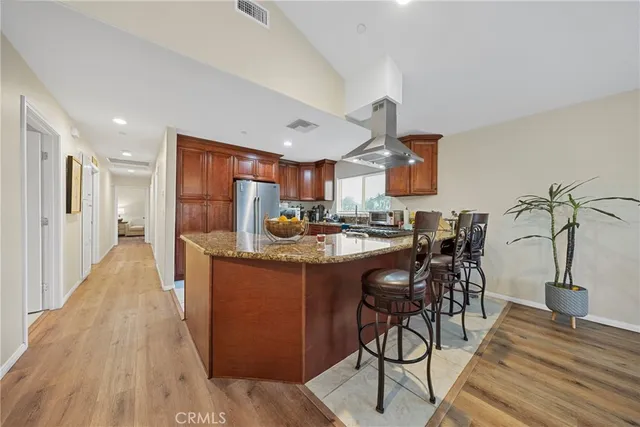 a kitchen with stainless steel appliances granite countertop a table chairs and a refrigerator