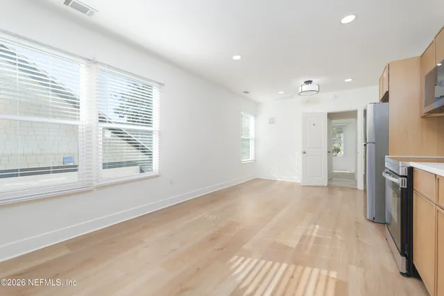 a view of empty room with wooden floor and a window