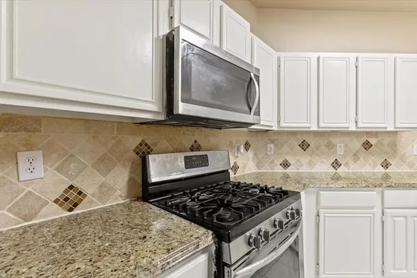 a kitchen with granite countertop a stove sink and cabinets