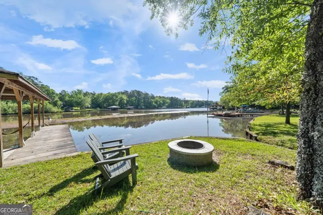 a view of a lake with a table and chairs next to a yard