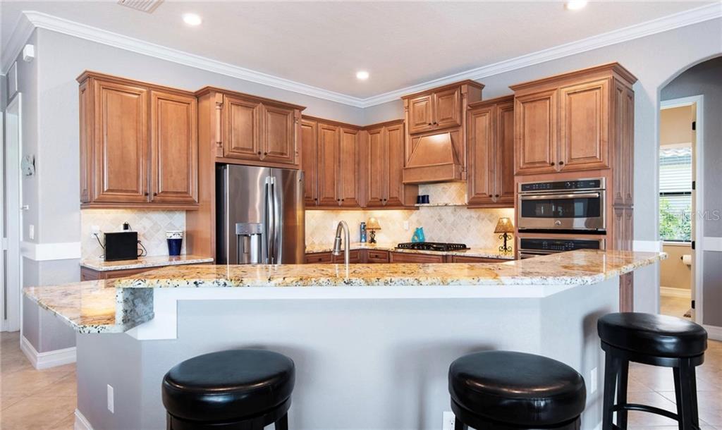 5543 Arnie Loop Bradenton, FL 34211 - Photo 33 of 45 a kitchen with stainless steel appliances granite countertop a sink refrigerator stove and microwave