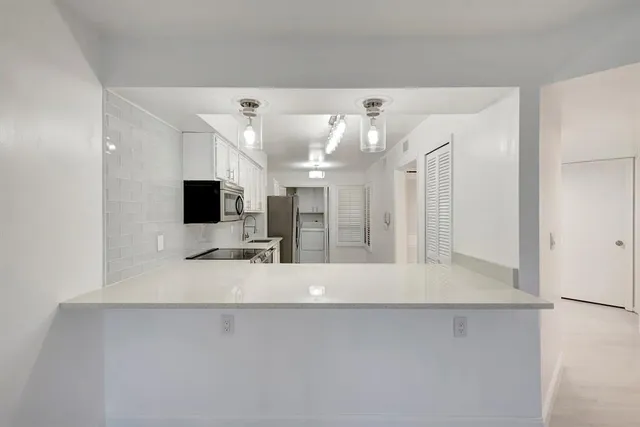 a kitchen with stainless steel appliances a refrigerator a stove a sink and white cabinets