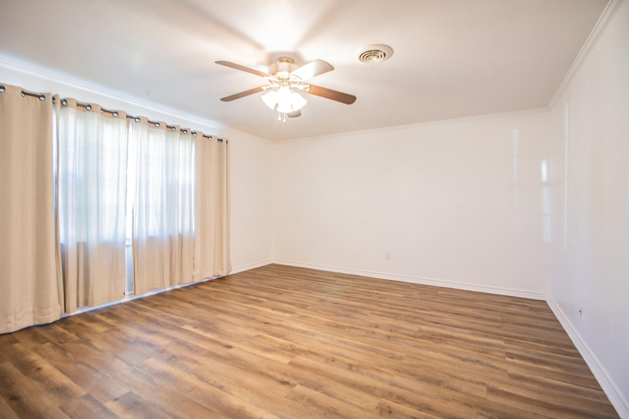 5503 9th Street Lubbock, TX 79416 - Photo 13 of 31 an empty room with wooden floor fan and windows