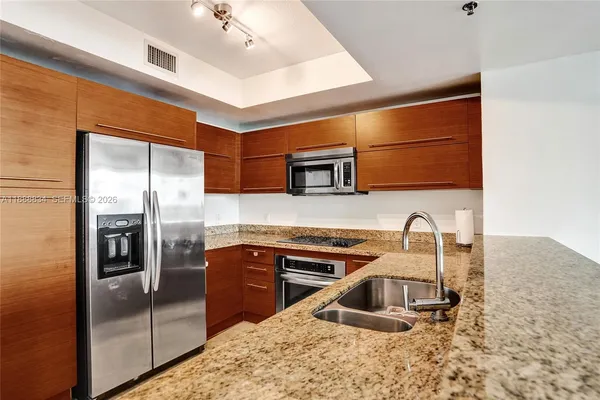 a kitchen with stainless steel appliances granite countertop a sink and a refrigerator