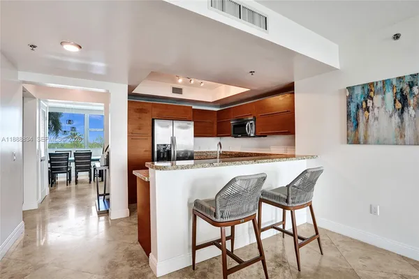 a kitchen with stainless steel appliances granite countertop table chairs and a refrigerator