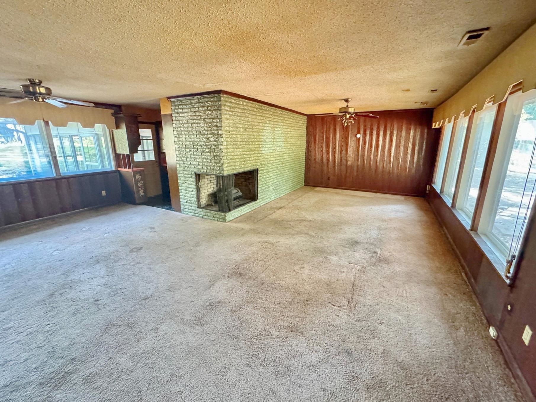 6014 Raleigh Lagrange Road Memphis, TN 38134 - Photo 8 of 19 Unfurnished living room with ceiling fan, carpet, a textured ceiling, and a fireplace