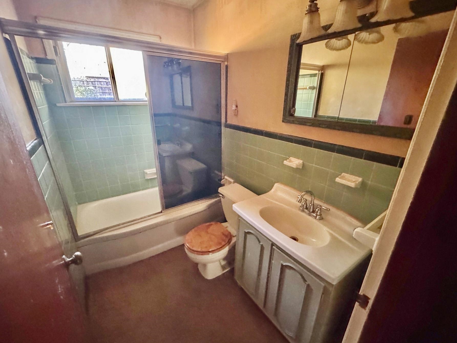 6014 Raleigh Lagrange Road Memphis, TN 38134 - Photo 10 of 19 Bathroom with bath / shower combo with glass door, tile walls, vanity, and wainscoting