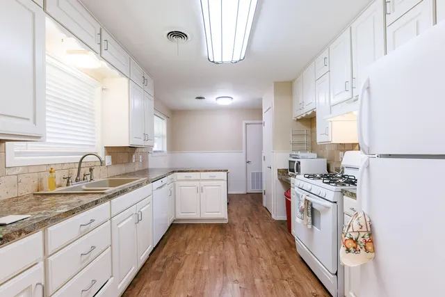 a kitchen with stainless steel appliances granite countertop a stove top oven a refrigerator a sink and dishwasher