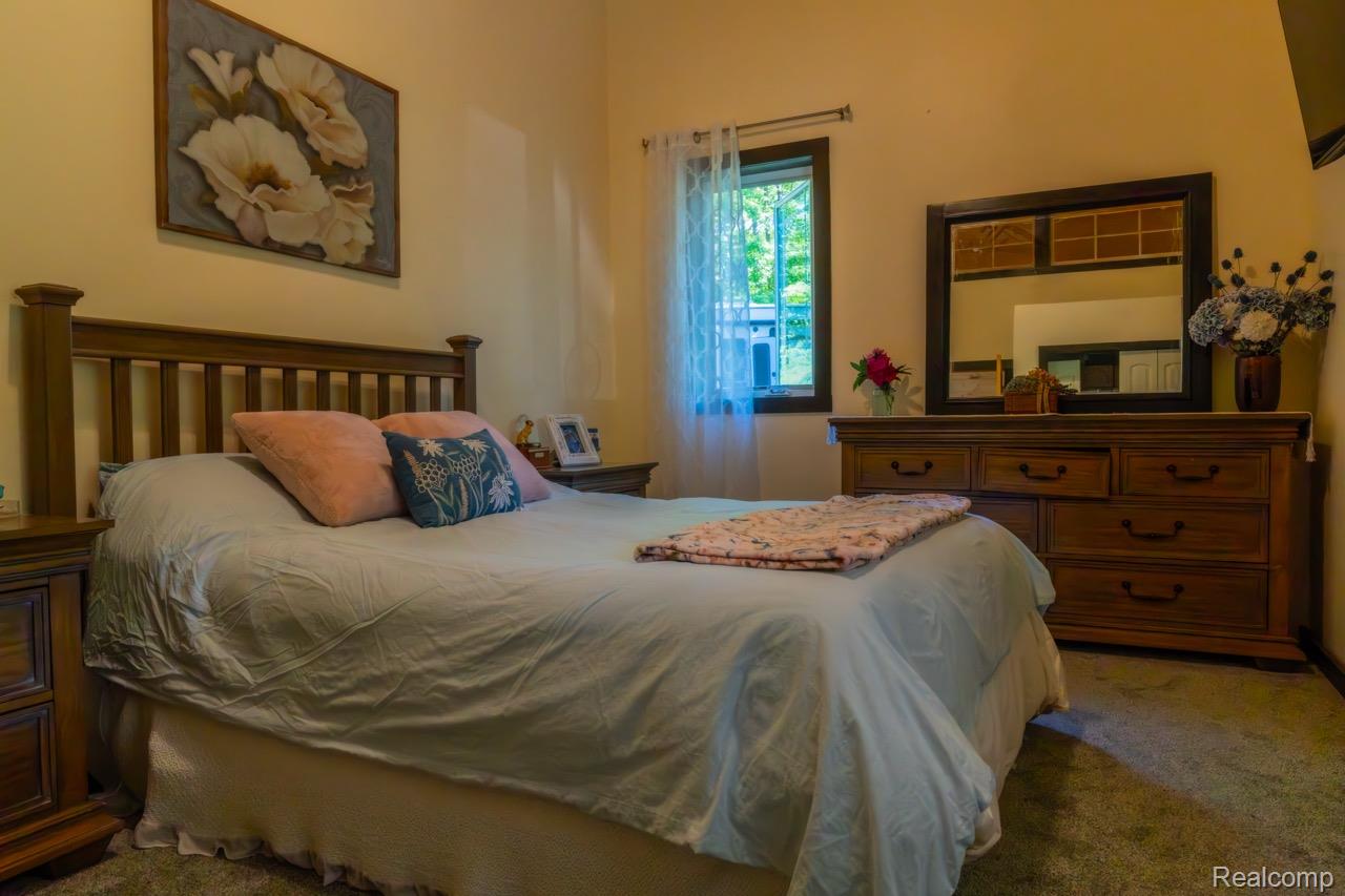 2418 South 41st Road South Cadillac, MI 49601 - Photo 16 of 57 Bedroom featuring light-toned walls, wood-finish bed frame, and wood-finish dresser with an attached mirror