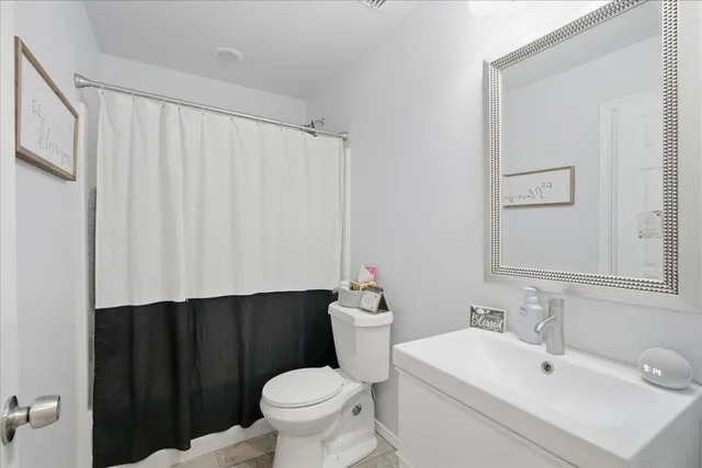 a bathroom with a sink a toilet a mirror and shower curtain