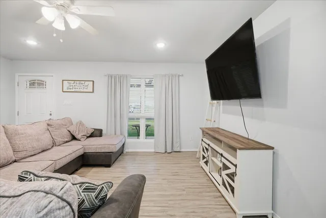 a living room with furniture a flat screen tv and a window