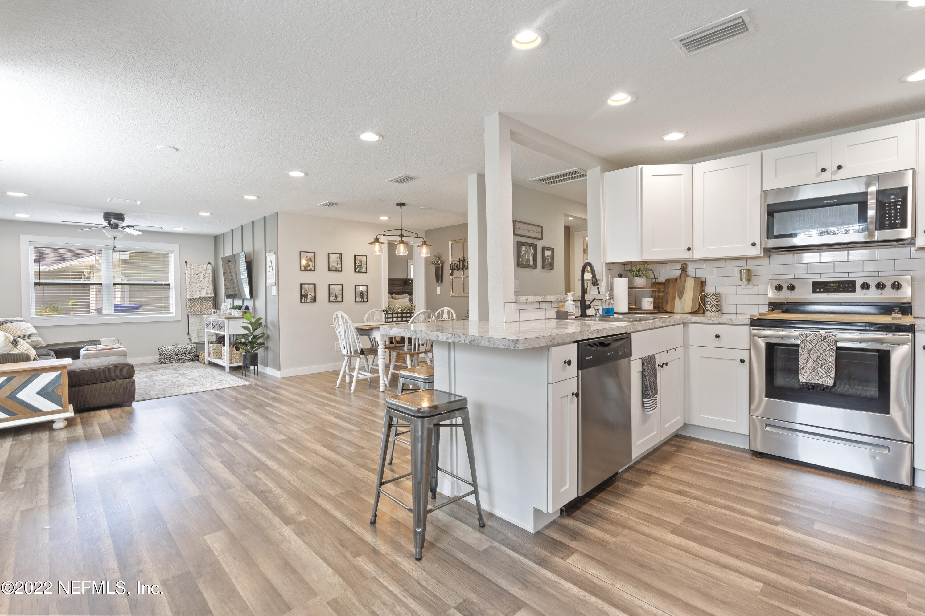 1032 Prince Road St. Augustine, FL 32086 - Photo 14 of 39 a kitchen with stainless steel appliances kitchen island granite countertop a stove a sink a refrigerator and white cabinets with wooden floor