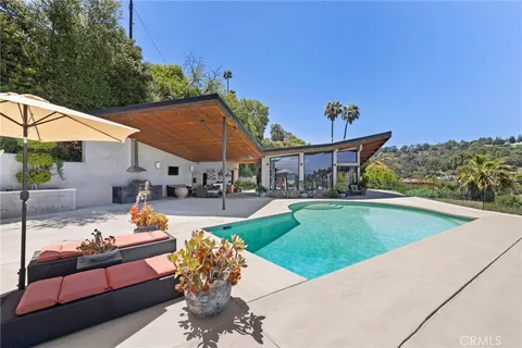 a view of a patio with couches table and chairs under an umbrella