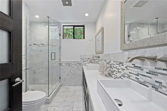 a bathroom with a granite countertop sink a toilet and shower