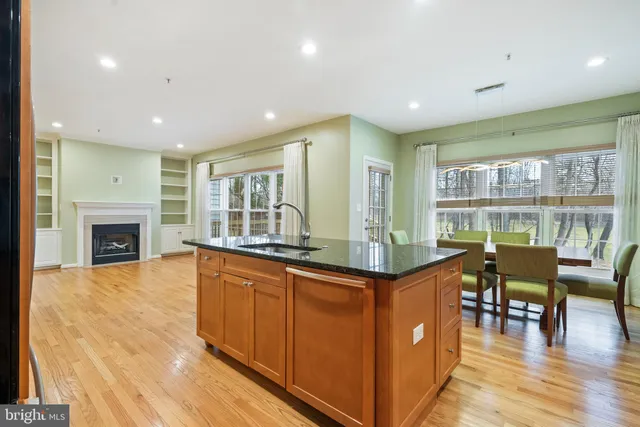 a dining hall with stainless steel appliances granite countertop a stove and cabinets with wooden floor