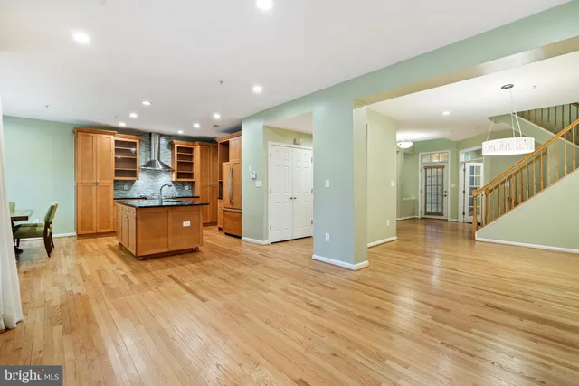 a view of a kitchen with kitchen island wooden floors granite counter tops and a view of living room
