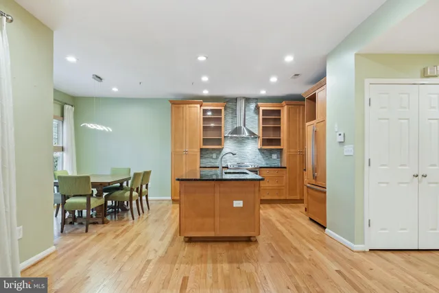 a dining hall with stainless steel appliances granite countertop a stove and chairs with wooden floor