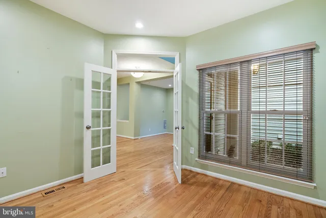 an empty room with wooden floor and windows