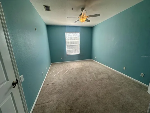 an empty room with windows and fan