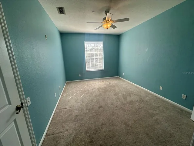 an empty room with windows and fan